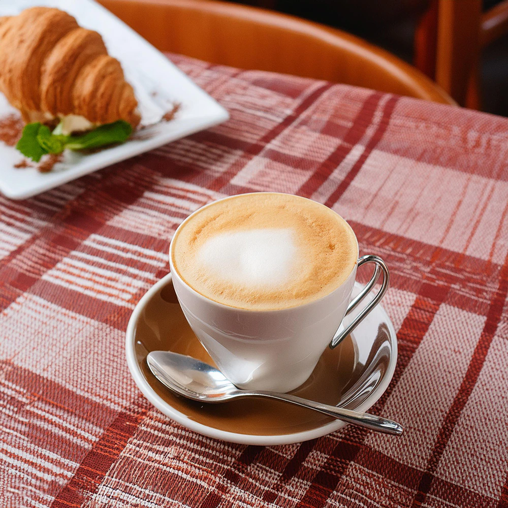 Smakowicie zaparzona kawa Macchiato podana w eleganckiej białej filiżance ze spodkiem